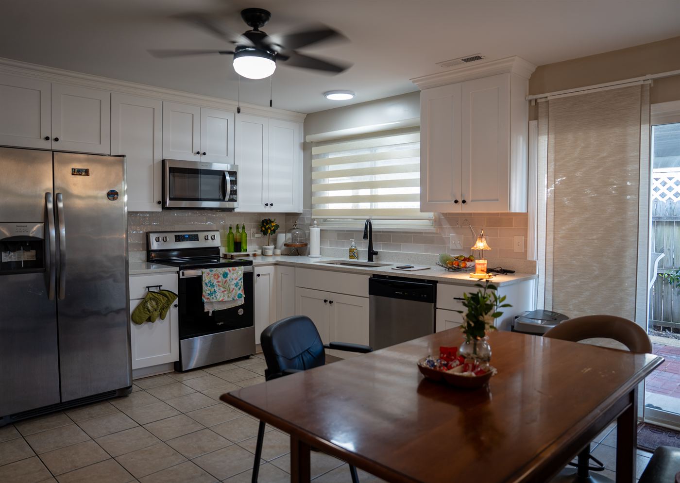 The kitchen and dining area at Comfort Living — bright white cabinetry, stainless appliances, family-style dining table set for the day's meal